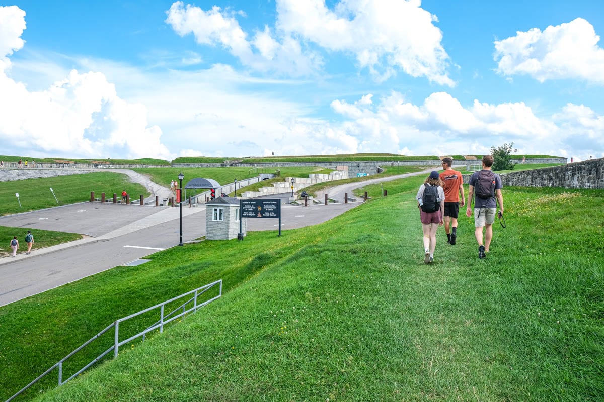 three people walking on grass approaching quebec citadel hill.