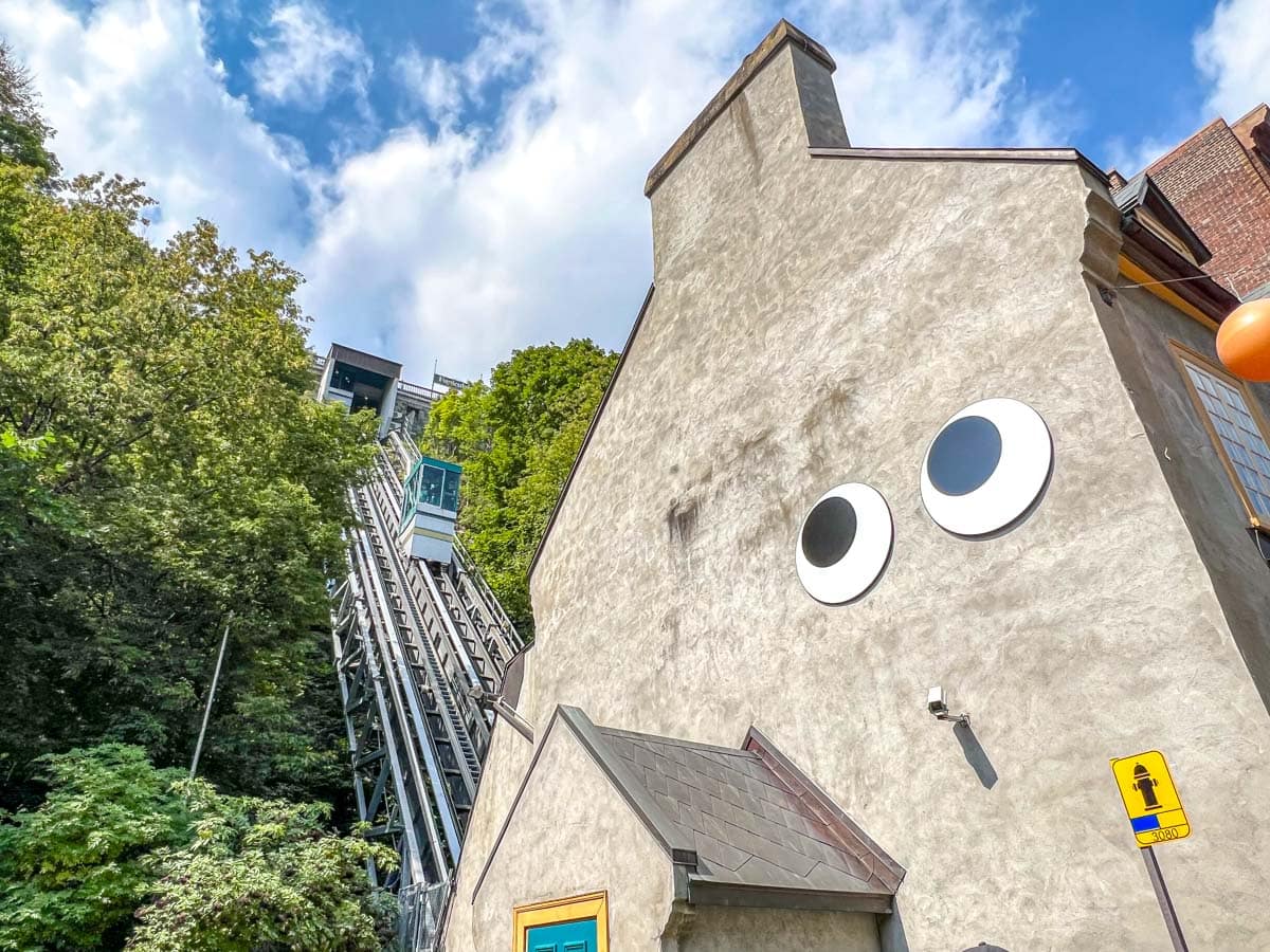 large building with eyeballs and funicular car behind going up hill.
