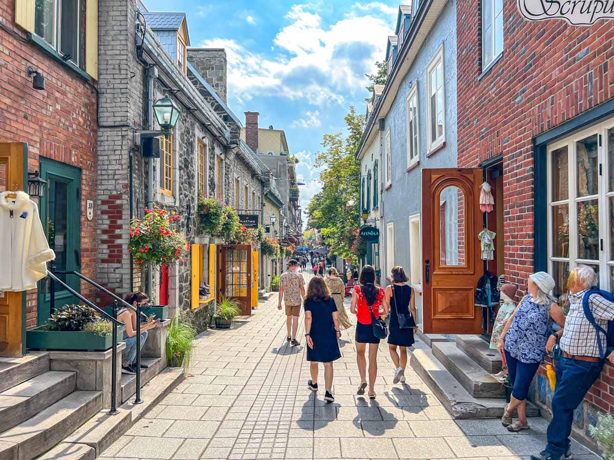 women walking down colourful old town street in quebec city.