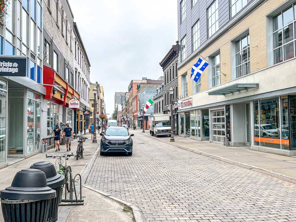busy city street with cars parked and shop fronts along sidewalk in saint-roch.