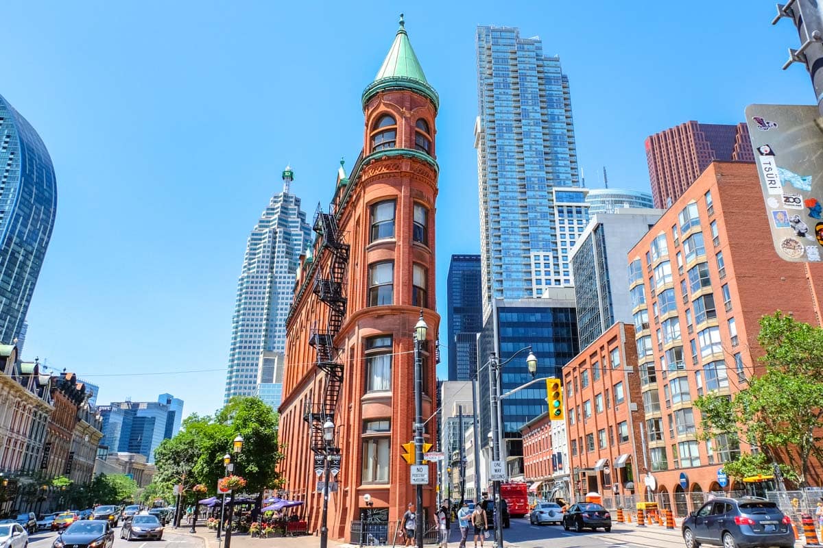thin red brick building with green cone top at street intersection in toronto.