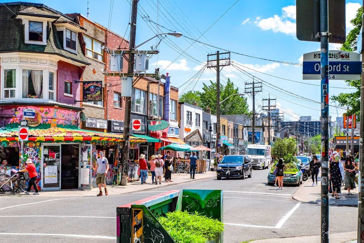 neighbourhood street with people and colourful shops in kensington market.